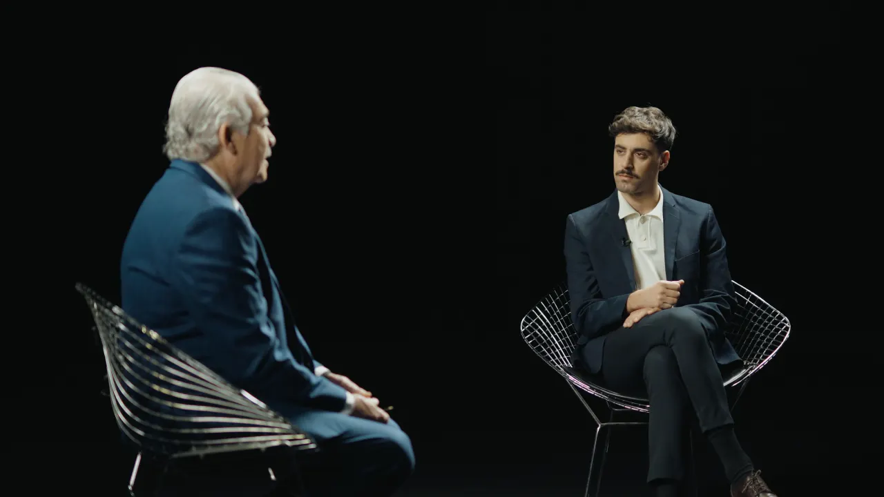 Entrevista uno a uno en sillas de rejilla sobre fondo negro para Cámara Abierta